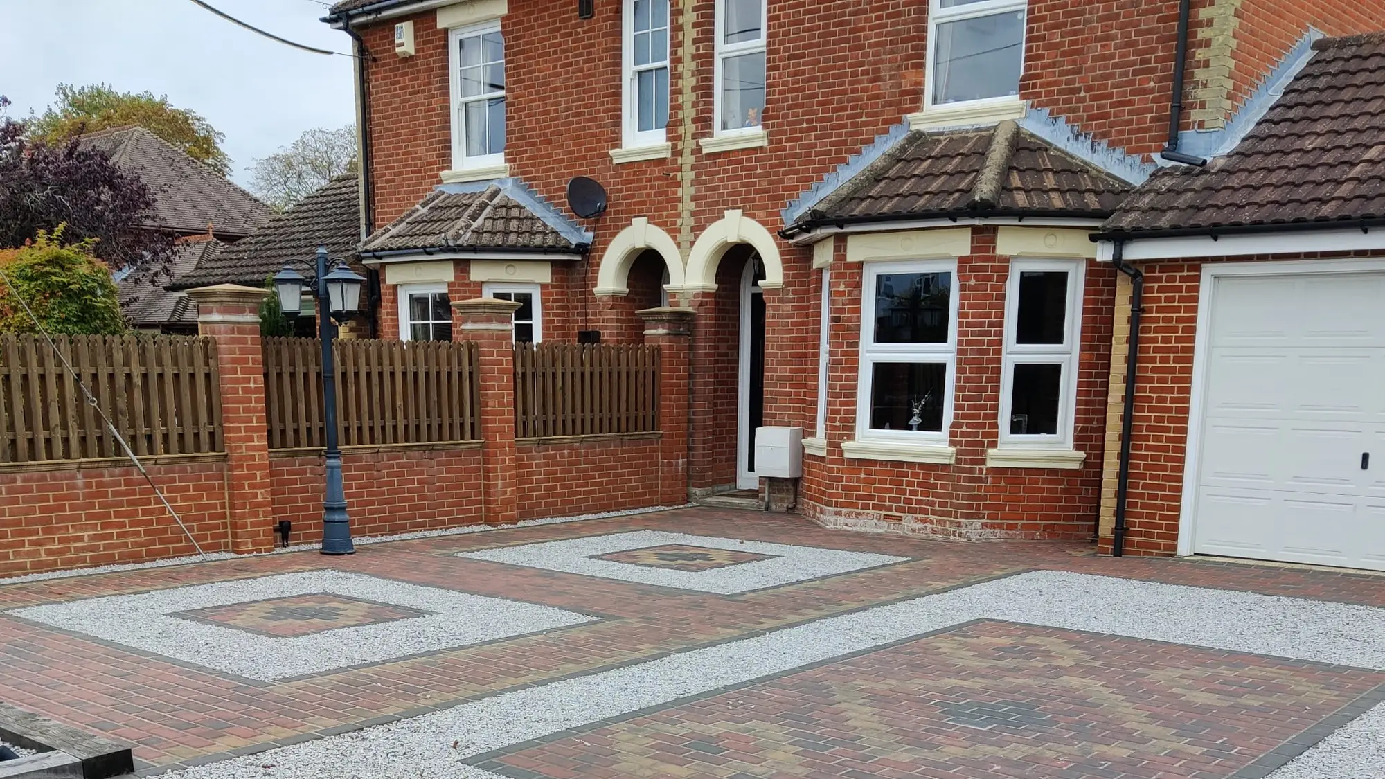 A block paved driveway with gravel inset panels to the front of a house